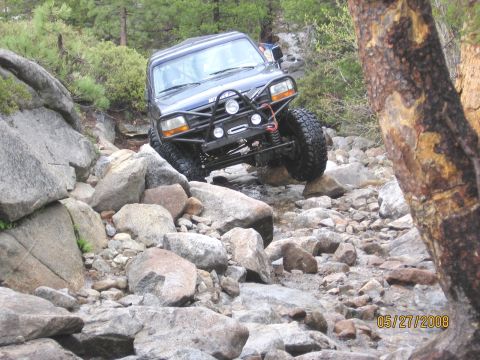 1994 Ford Bronco - This 1994 Ford Bronco is tackling a challenging off-road course with significant rock obstacles.