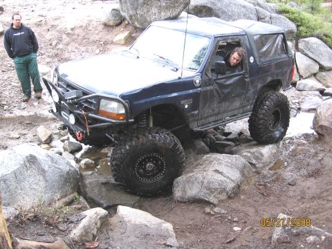 1994 Ford Bronco - This 1994 Ford Bronco is shown navigating a challenging off-road course with large rocks and water.