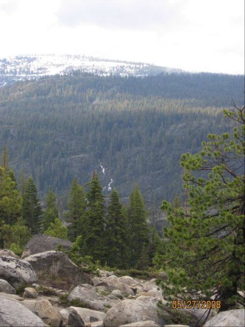 1994 Ford Bronco - A scenic view of a mountainous forest landscape with rocks in the foreground and snow on the peaks.