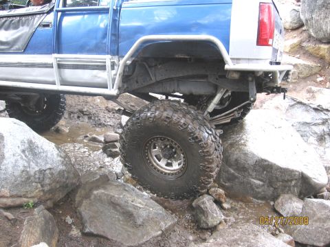 1994 Ford Bronco - This modified pickup truck is shown off-roading over large rocks and through water.
