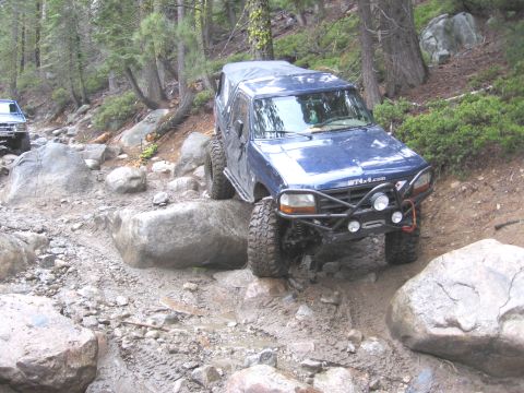 1994 Ford Bronco - Blue 1994 Ford Bronco tackles a challenging rocky trail with a second vehicle in the background.