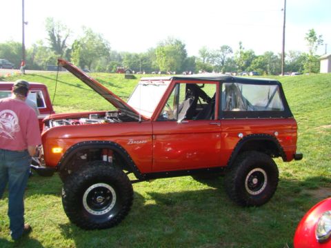 1994 Ford Bronco - This orange Ford Bronco is displayed with its hood open, revealing the engine compartment.