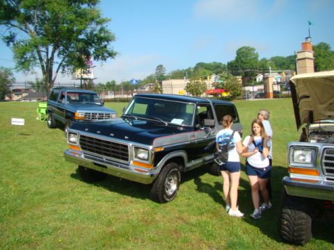 1994 Ford Bronco - A black and gray Ford Bronco is parked on a grassy field with other vehicles and people.