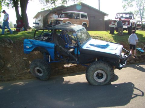 1994 Ford Bronco - Modified 1994 Ford Bronco with a roll cage and large tires, parked outdoors with other vehicles in the background.