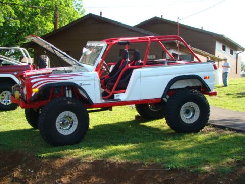 1994 Ford Bronco - Modified Ford Bronco with custom roll cage and off-road tires parked on grass.