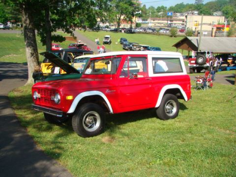 1994 Ford Bronco - A red 1978 Ford Bronco is parked on a grassy field next to other vehicles.