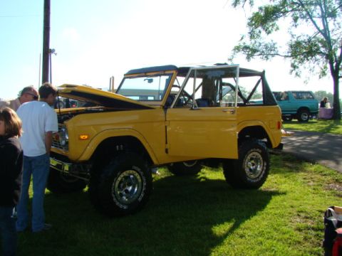 1994 Ford Bronco - Yellow 1978 Ford Bronco with hood open, parked on grass at an outdoor event.
