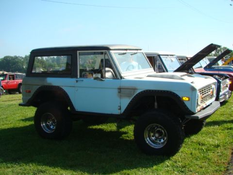 1994 Ford Bronco - A classic Ford Bronco is displayed outdoors with other vehicles, some with their hoods open.
