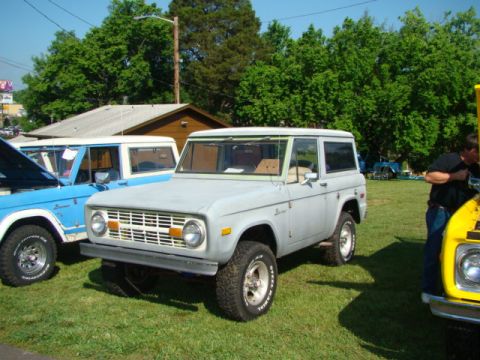 1994 Ford Bronco - A light gray Ford Bronco is parked on a grassy field next to other vehicles.