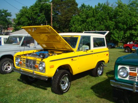 1994 Ford Bronco - Yellow 1978 Ford Bronco on display with hood open, parked on grass.