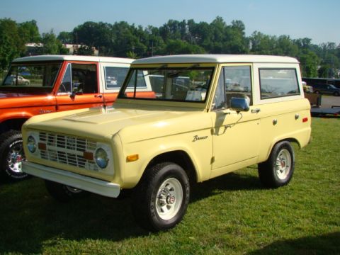 1994 Ford Bronco - Two classic Ford Broncos are parked on a grassy field under a clear sky.