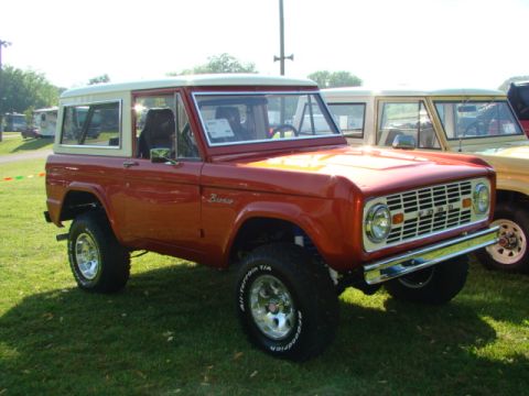 1994 Ford Bronco - A red 1978 Ford Bronco is parked on a grassy field next to another Bronco.