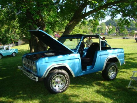 1994 Ford Bronco - A blue Ford Bronco, likely from the late 1970s, is displayed with its hood open on a sunny day, with another vehicle visible in the backgro…