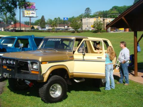 1994 Ford Bronco - A two-tone gold and cream Ford Bronco is parked on grass with people standing nearby.
