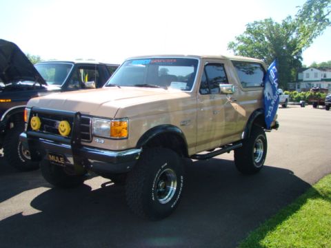 1994 Ford Bronco - Modified Ford Bronco with large tires and a blue flag attached to the rear fender.