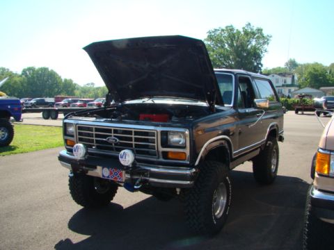 1994 Ford Bronco - This Ford Bronco has its hood up, revealing the engine bay. Other vehicles are parked nearby.