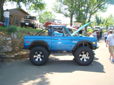 1994 Ford Bronco - A modified blue Ford Bronco is displayed at an outdoor event with other vehicles.