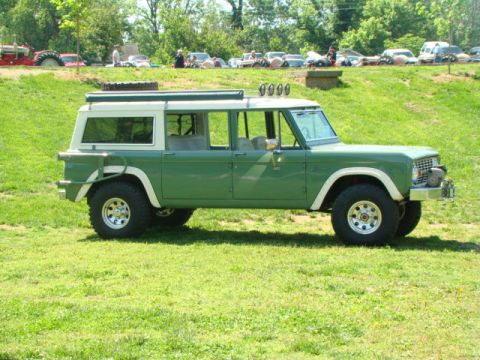 1994 Ford Bronco - This four-door SUV, likely from the 1970s, sits on a grassy hill with other vehicles in the background.