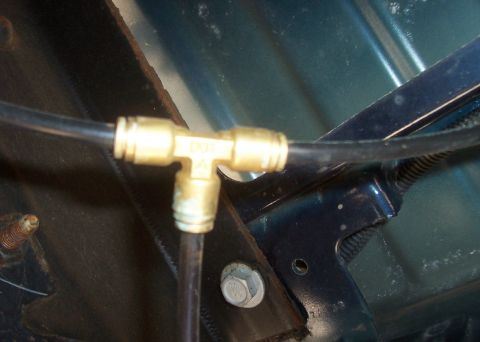 1994 Ford F-150 - A brass tee fitting connects two black lines, likely part of an air system on a vehicle.
