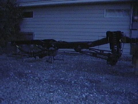 1992 Ford Bronco - The underside of a vehicle, showing the frame and suspension, is visible in this dimly lit outdoor shot.