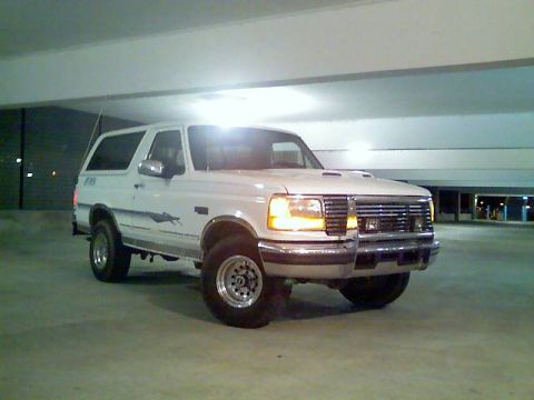 1996 Ford Bronco - This white SUV is parked in a concrete garage with overhead lighting.