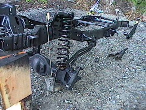 1992 Ford Bronco - Frame and suspension components are shown disassembled on a gravel surface, with the Supermotors.net logo in the lower right corner.