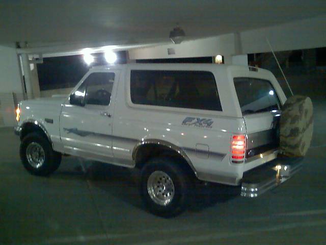 White 1996 Ford Bronco parked in garage, rear quarter view with spare tire mounted on tailgate