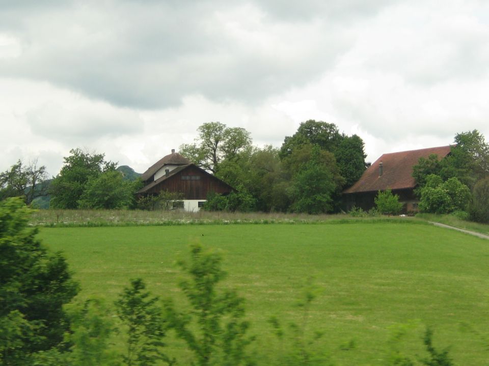 Farm buildings and green fields under a cloudy sky
