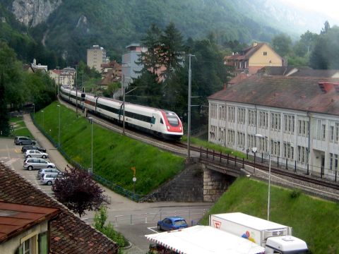 1996 Ford Bronco - A modern train moves along a scenic route, with parked cars and buildings visible in the background.