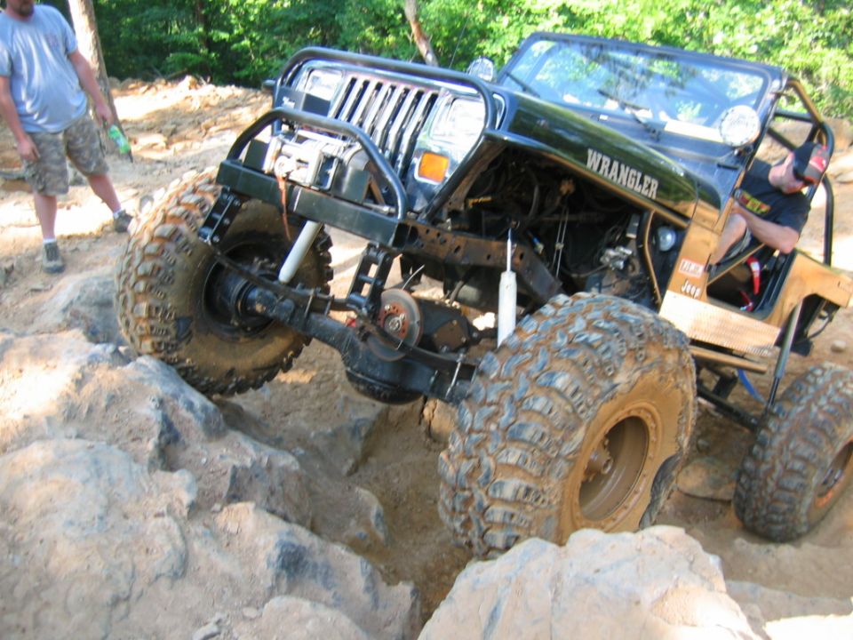 Black Jeep Wrangler with large tires on rocky terrain
