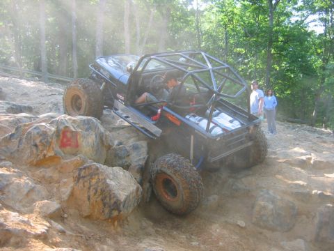1992 Ford Mustang - This heavily modified off-road vehicle navigates a challenging rocky incline with two people inside.