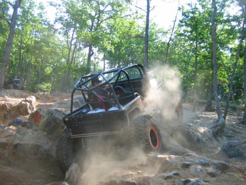 1992 Ford Mustang - An off-road vehicle navigates a rocky trail, creating a cloud of dust as it climbs.
