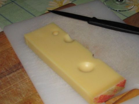 1996 Ford Bronco - A block of Swiss cheese with characteristic holes sits on a cutting board, ready to be sliced.