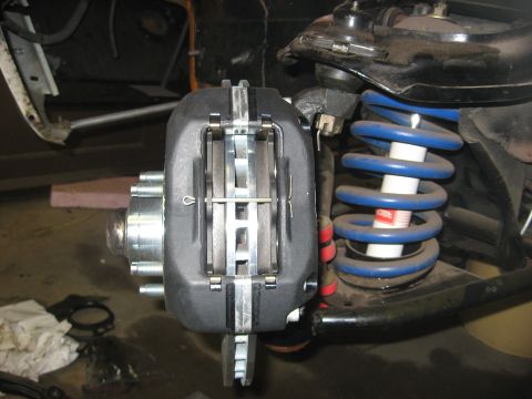 1978 Ford Mustang II - Close-up of a vehicle's front brake assembly, showing the caliper, pads, rotor, and suspension components.