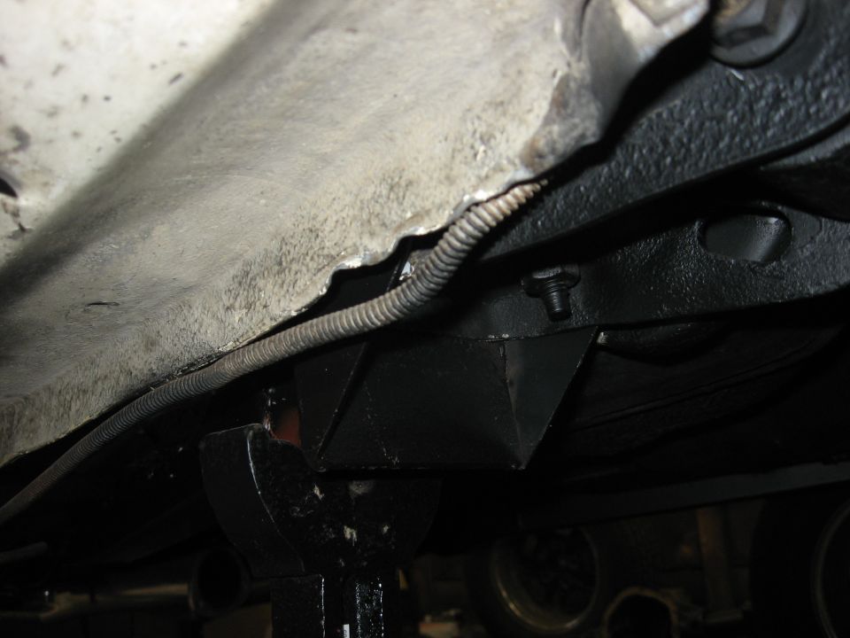 Undercarriage of a vehicle with black painted frame components and a wire conduit