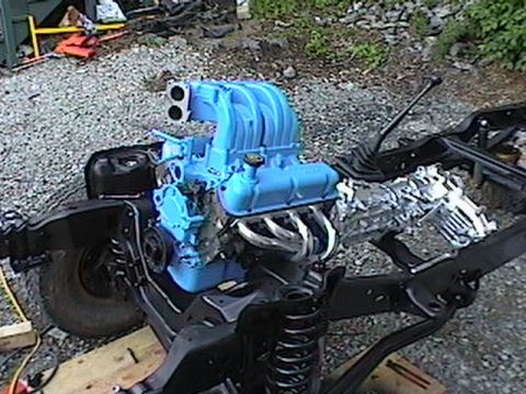 1992 Ford Bronco - Engine and chassis components are laid out on a gravel surface, possibly for assembly or repair.