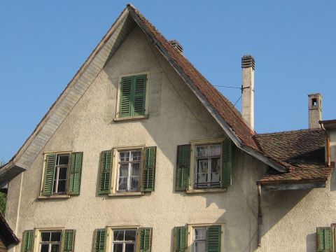 1996 Ford Bronco - A close-up view of a building's exterior shows multiple windows with green shutters and two chimneys against a bright blue sky.
