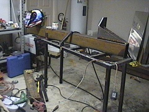 1992 Ford Bronco - A workshop setting with a metal structure being worked on, surrounded by tools and equipment.