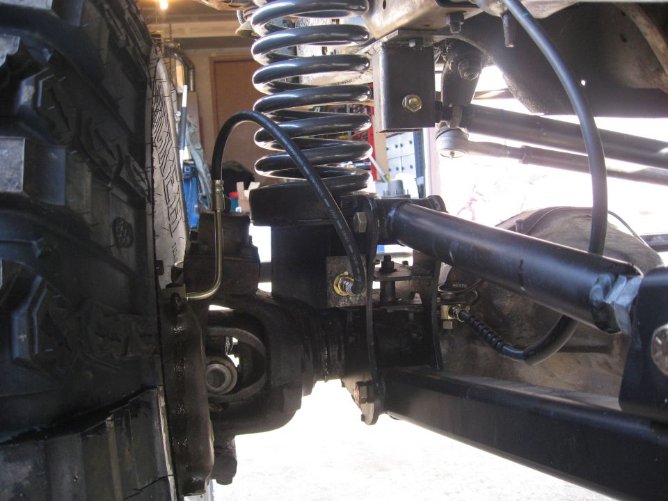 Coil-spring front suspension and axle under a lifted truck in a garage