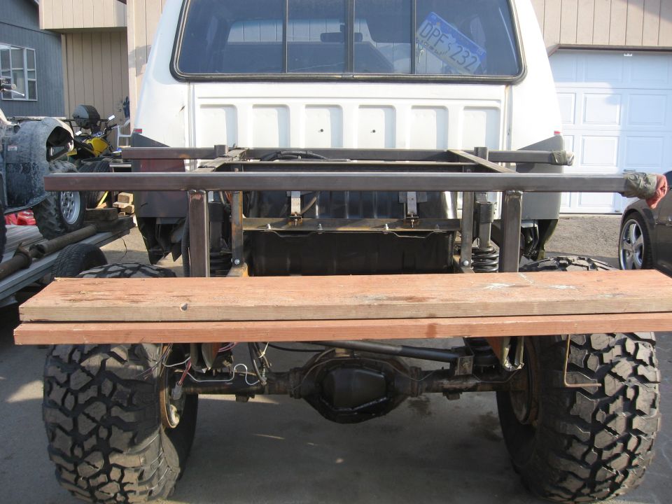 Rear of a white SUV chassis under construction with bare frame and axle