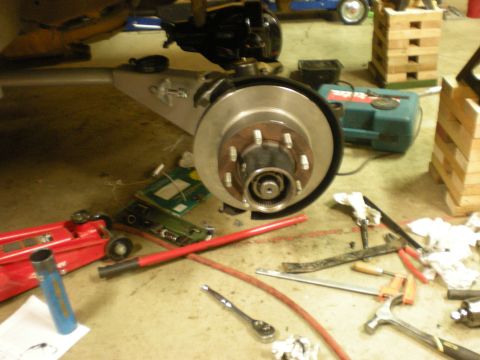 1993 Ford Bronco - Vehicle brake rotor and hub assembly with various tools on the floor.