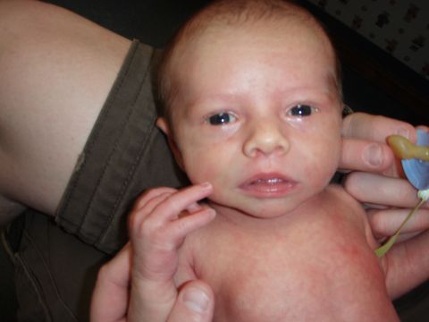 1997 Ford F-250 - A close-up photo of a newborn baby, with adult hands holding them and a pacifier visible.