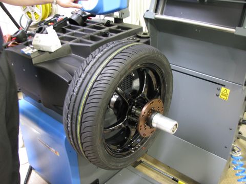 2003 Ford Focus - A tire is mounted on a wheel balancing machine, with a person adding fluid.