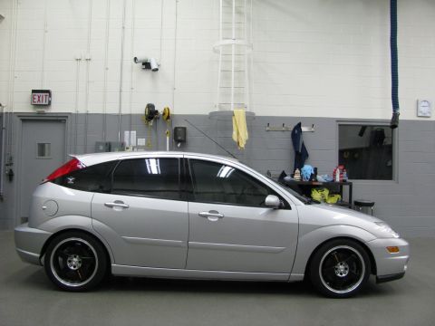 2003 Ford Focus - A silver hatchback is viewed from the side in a garage setting.