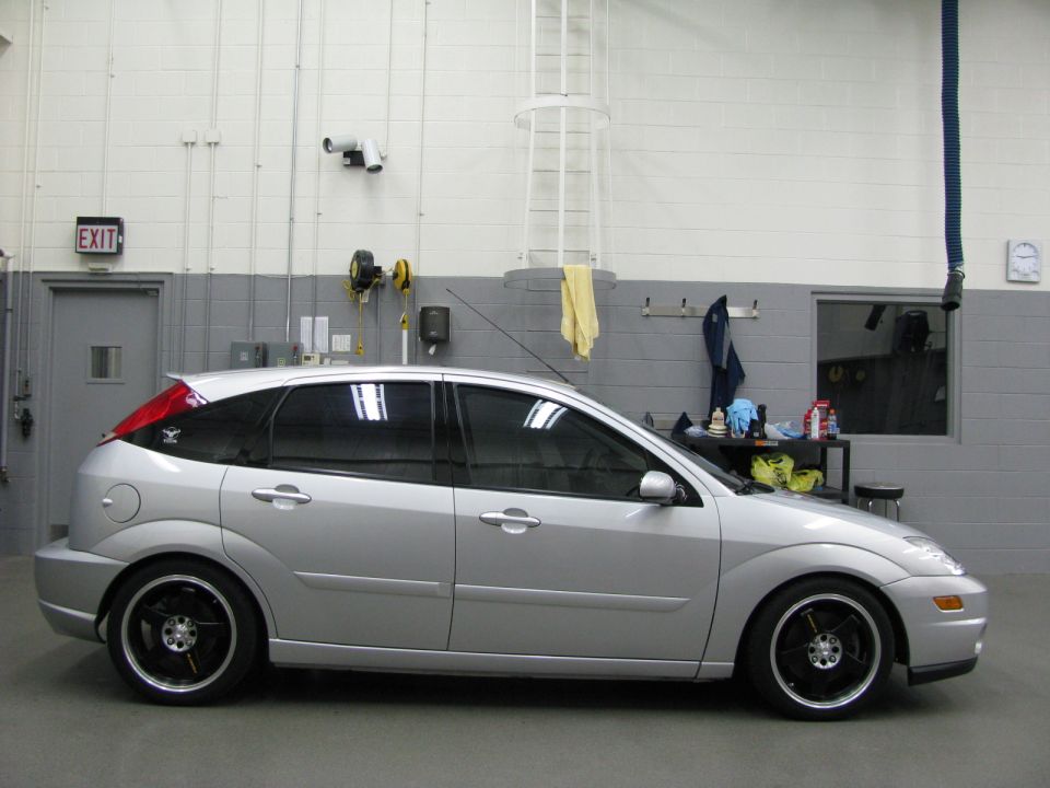 Silver hatchback with black rims parked inside a garage