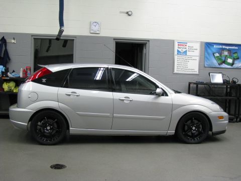 2003 Ford Focus - Silver 2003 Ford Focus hatchback with custom black rims parked inside a service bay.