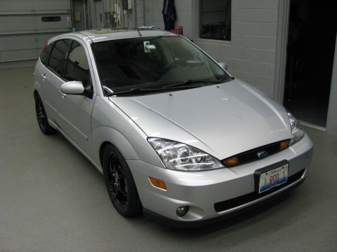2003 Ford Focus - A silver 2003 Ford Focus hatchback is shown from the front-right in a garage setting.