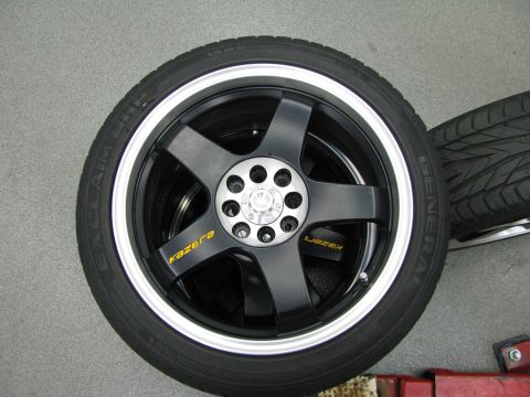 2003 Ford Focus - Close-up of black Kazera rims with a silver lip, mounted on General tires. Another tire is visible in the background.