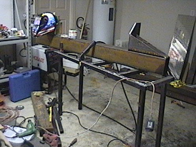 Welding project setup with a helmet on a stand, metal beams, and tools on the floor