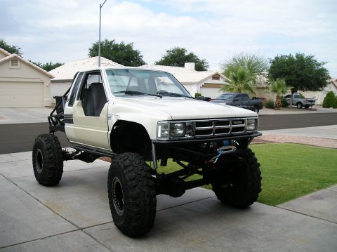 1986 Toyota Hilux - This modified Toyota pickup features a significant lift and oversized tires, ready for off-road adventures.